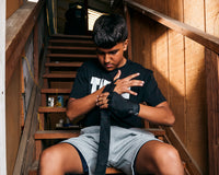 variant:lifestyle::TITLE Boxing Advanced Semi-Elastic Assorted Hand Wraps (10 Pair) boxer wrapping hands in black hand wrap