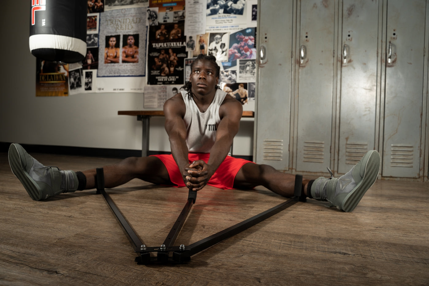variant:lifestyle::TITLE Boxing Deluxe Leg Stretch guy using leg stretch in boxing gym environment