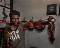 variant:lifestyle::TITLE Boxing Elliptical Resistance Bands Set with a boxer using the red band