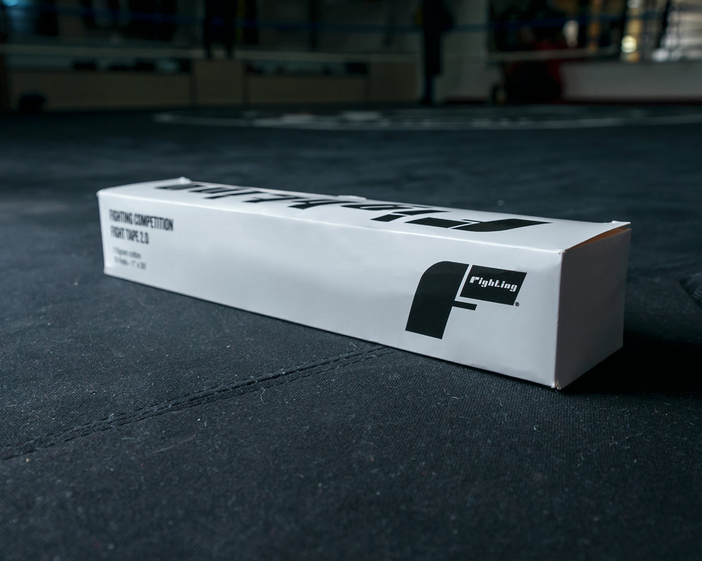 variant:lifestyle::Fighting Sports Competition Fight Tape 2.0 (10 Rolls) in the box on the floor of a boxing gym