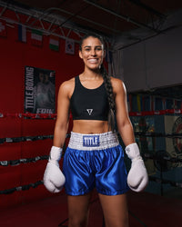 variant:black::TITLE Boxing Pro Compression Ascent Sports Bra lady with blue shorts in ring