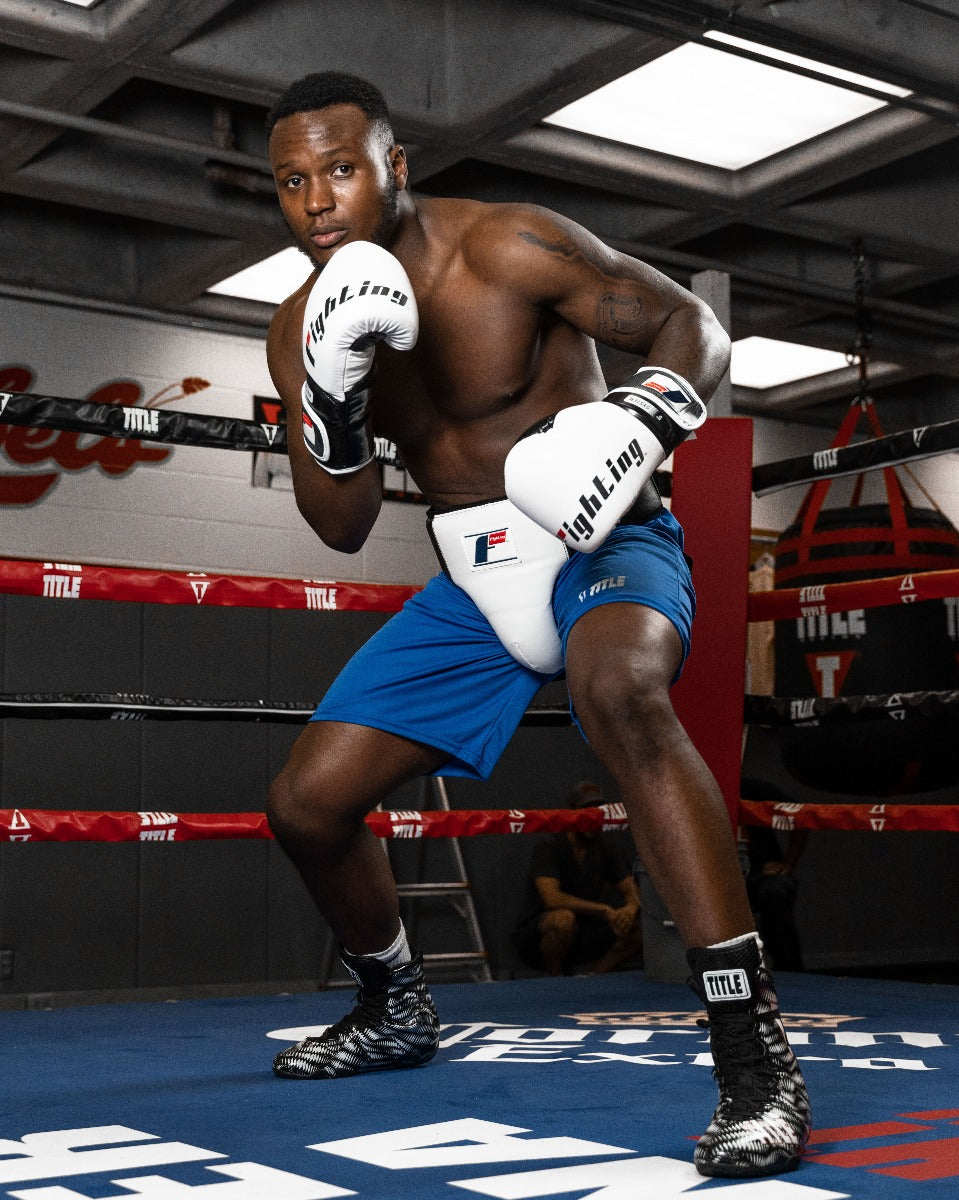 variant:lifestyle::Fighting Deluxe Groin & Ab Protector 2.0 guy posing in groin protector with boxing gloves and inside of boxing ring