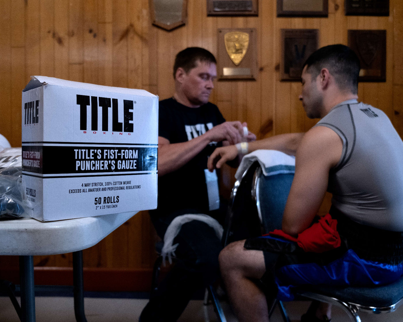 variant:lifestyle::TITLE Boxing Fist-Form Puncher’s Gauze in a boxing gym with a trainer and a fighter