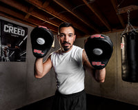 variant:lifestyle::TITLE Boxing Gel World Contoured Punch Mitts coach holding up mitts