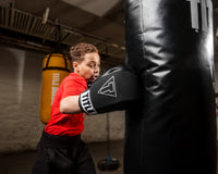 variant:black::TITLE Boxing Gel Washable Fitness Gloves 3.0 kid hitting a bag