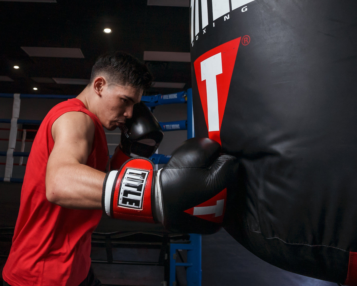 variant:Black/White/Red::TITLE Boxing Gel Weighted Boxing Gloves person wearing boxing gloves punching heavy bag