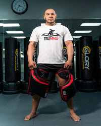 variant:lifestyle::TITLE MMA Gel Thai Style Thigh Pads 2.0 man posing with pads