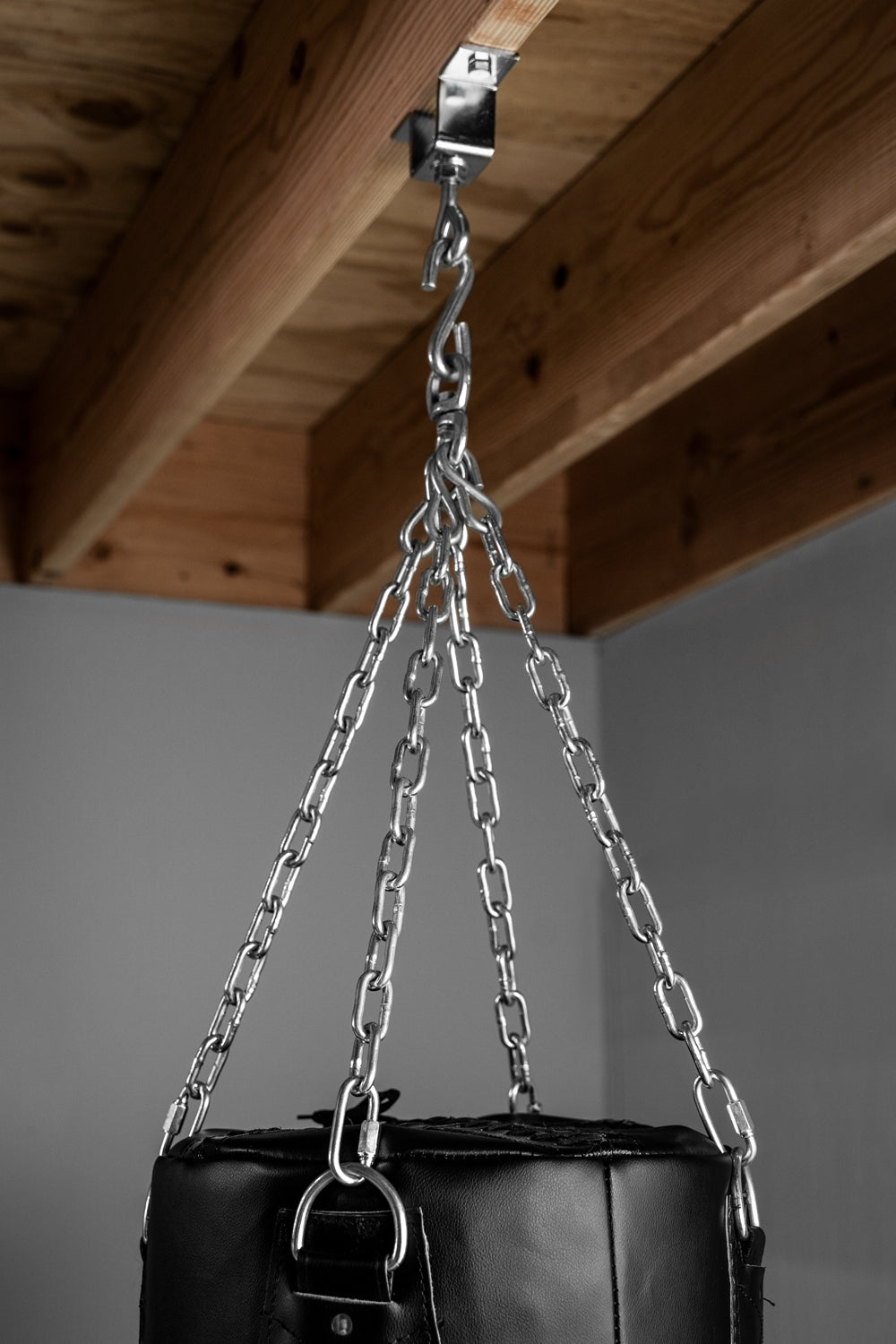 variant:lifestyle::TITLE Boxing Heavy-Duty Heavy Bag Chain & Swivel - Up To 150 lbs in use on a wood beam with a heavy bag
