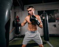 variant:black::TITLE Boxing Ko-Vert Bag Gloves guy boxing wearing boxing gloves in gym with heavy bags