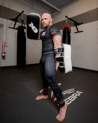 variant:black/white/grey::TITLE MMA Air Raid Thai Pads (Pair) guy in standing pose