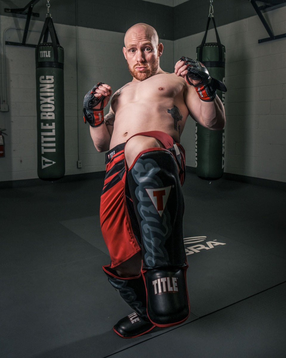 variant:lifestyle::TITLE Muay Thai Pao Shin-Instep Guards 2.0 man kneeing forward