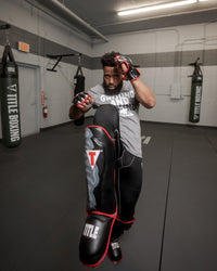 variant:lifestyle::TITLE Muay Thai Pao Shin-Instep Guards 2.0 man blocking with his leg