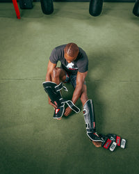 variant:lifestyle::TITLE MMA Perform World Pro Shin Guards 2.0 top view of man putting on guards
