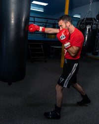 variant:red/white:Pro Mex Professional Lace Sparring Gloves V3.0 guy hitting bag right jab