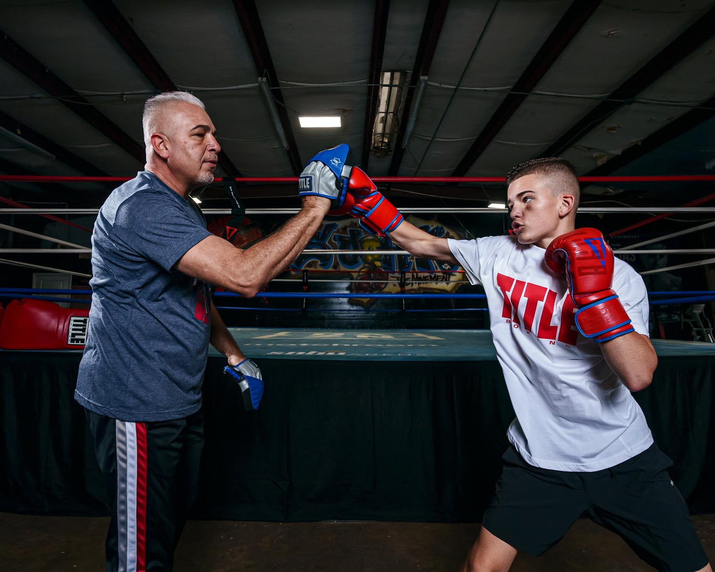 variant:lifestyle::TITLE Platinum Perilous Micro Palm Mitts kid and coach training in boxing gym