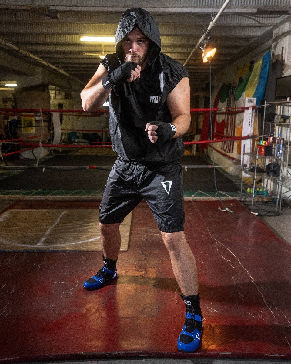 variant:lifestyle::TITLE Boxing Pro Set Vulcanized Rubber Sauna Suit With Hood guy wearing boxing gear posing in boxing gym setting
