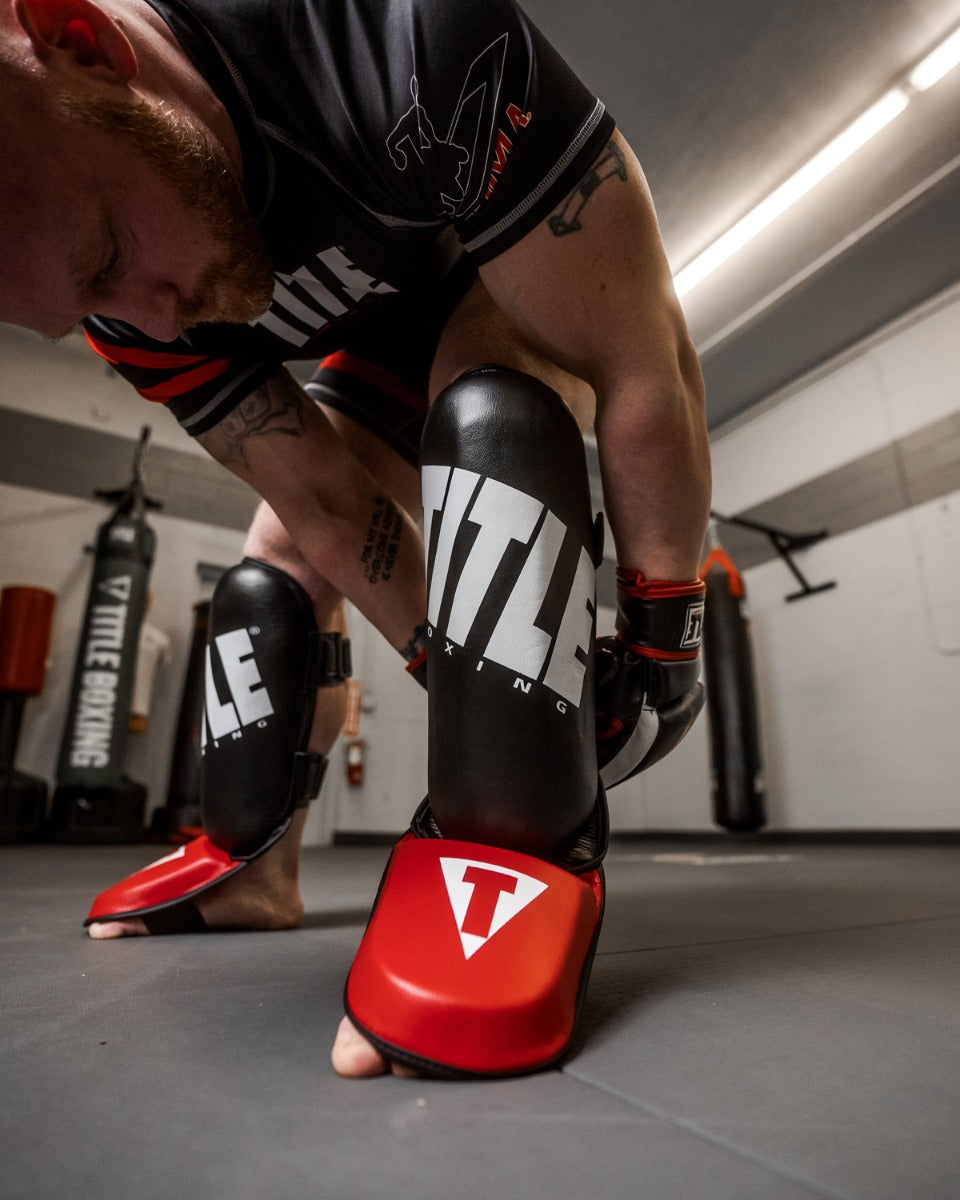 variant:lifestyle::TITLE Boxing Pro Style Shin & Instep Guards 3.0 guy putting on shin guards