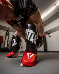 variant:lifestyle::TITLE Boxing Pro Style Shin & Instep Guards 3.0 guy putting on shin guards