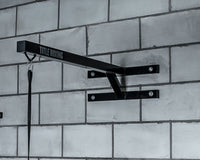 variant:lifestyle::TITLE Boxing Space Saver Wall Mount Bag Hanger 2.0 hanging on the wall of a boxing gym