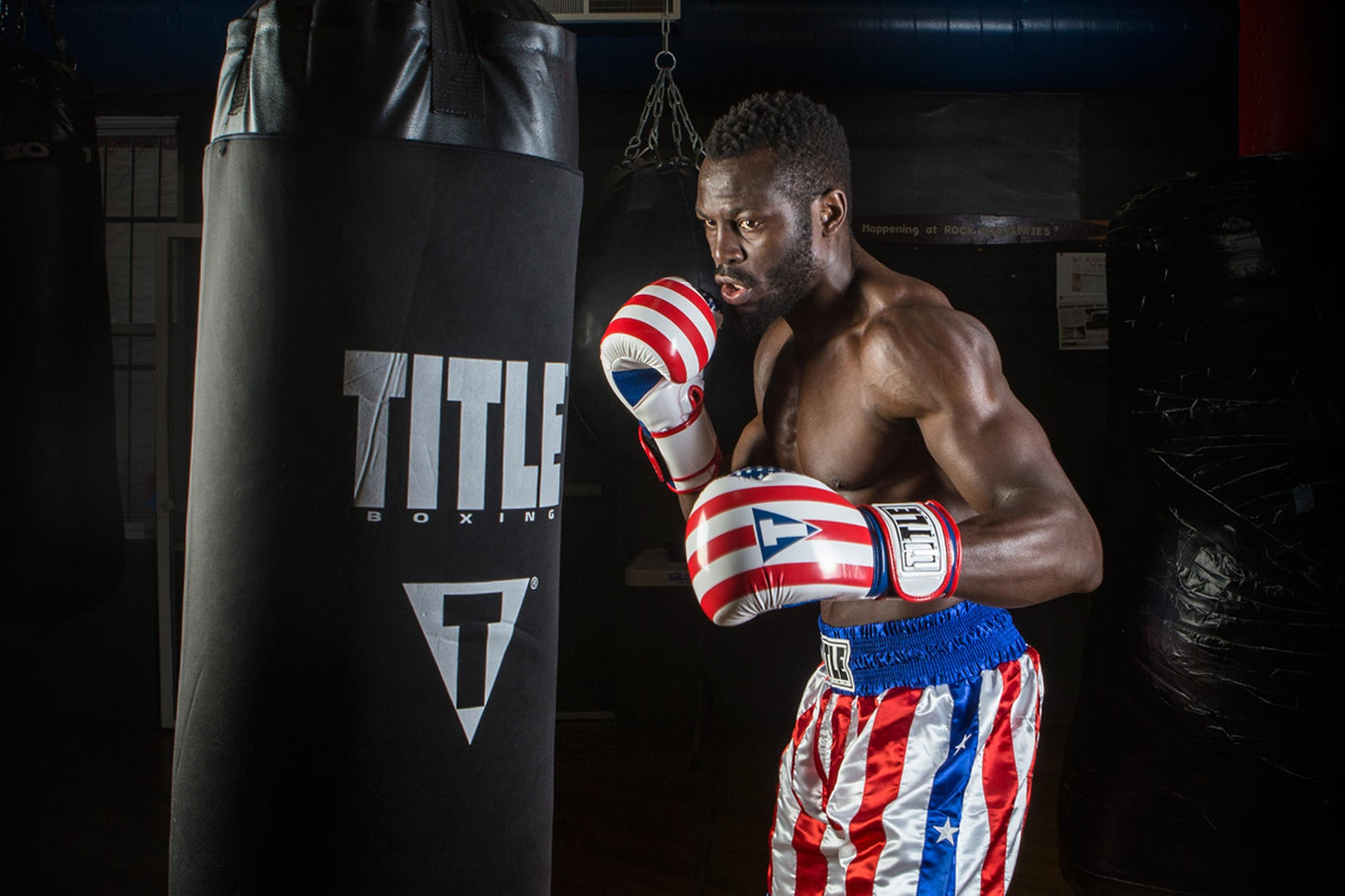 variant:lifestyle::TITLE Boxing Infused Foam Combat USA Training Gloves guy hitting bag