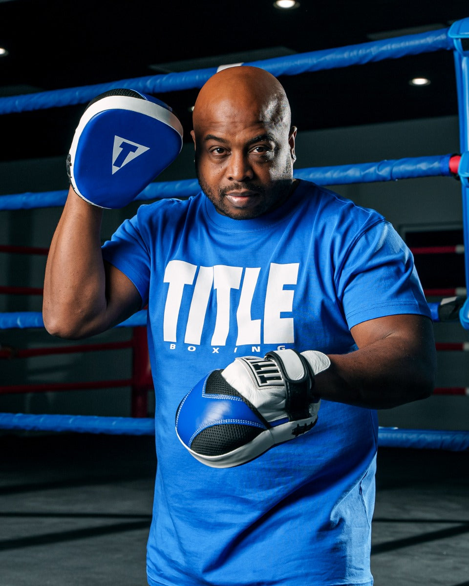 variant:Blue/White::TITLE Boxing Iconic Block Muscle Tee man posing in tee and punch mitts