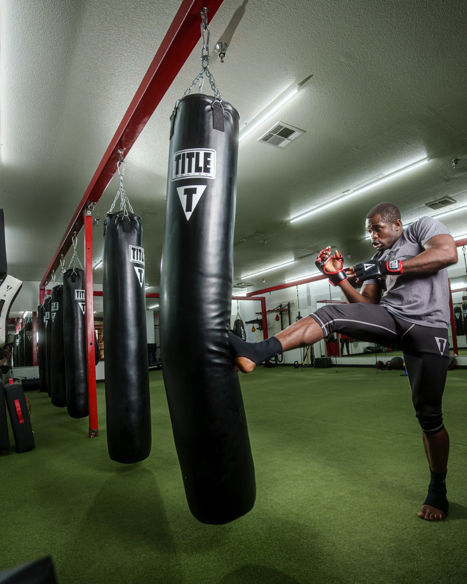 variant:lifestyle::TITLE Boxing 100lb Synthetic Thai Heavy Bag hanging in a boxing gym