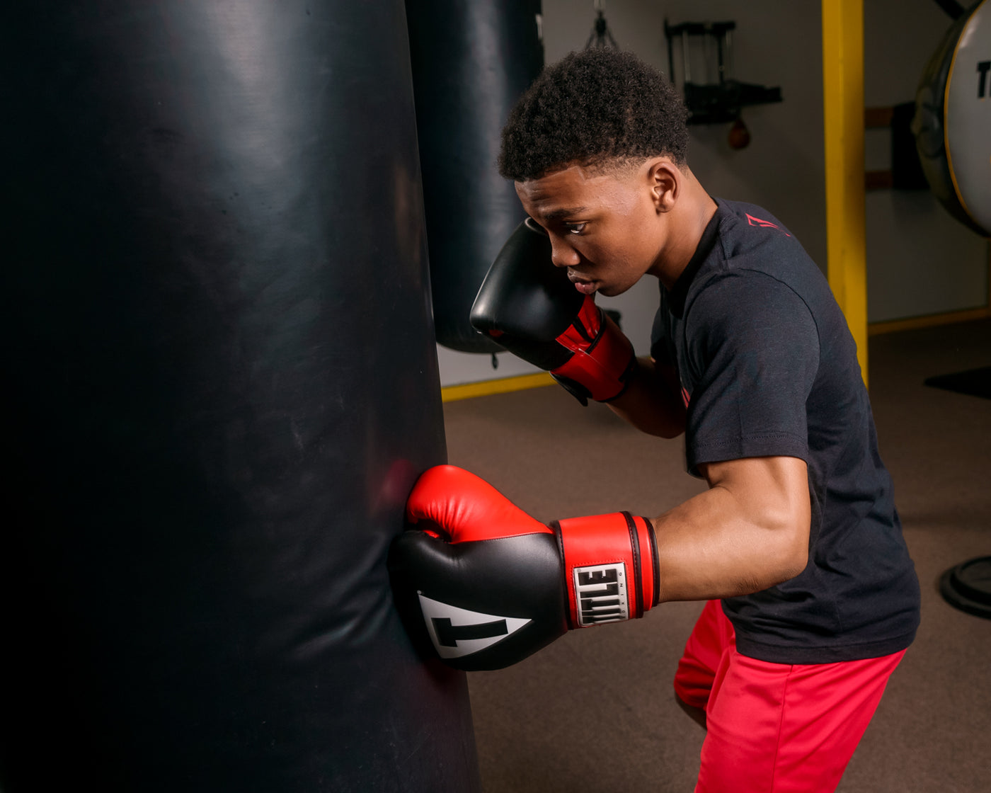variant:lifestyle::TITLE Boxing Pro Style Heavy Bag Gloves man wearing gloves hitting heavy bag