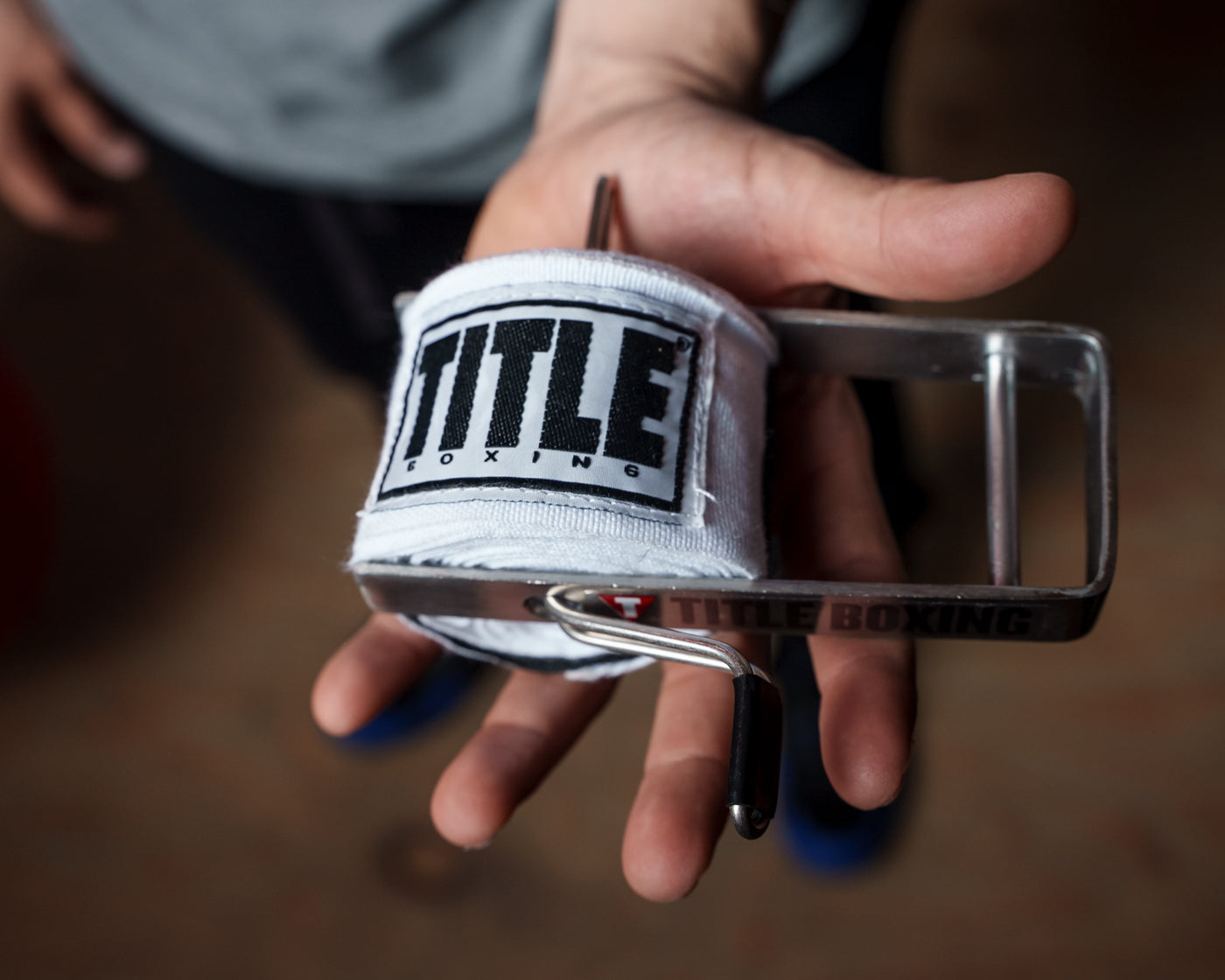 variant:lifestyle::TITLE Boxing Portable Zip Hand Wrap Roller in a mans hand with a rolled hand wrap